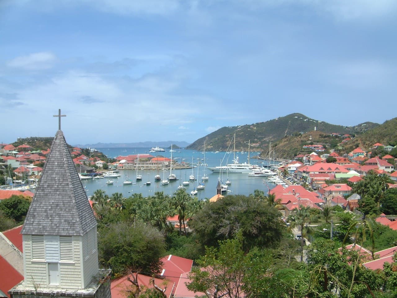 Gustavia harbor lined with superyachts below green hills on St. Barthelemy