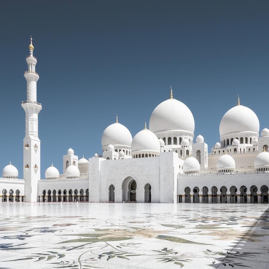 Sheikh Zayed Grand Mosque white domes and minarets glowing at twilight in Abu Dhabi
