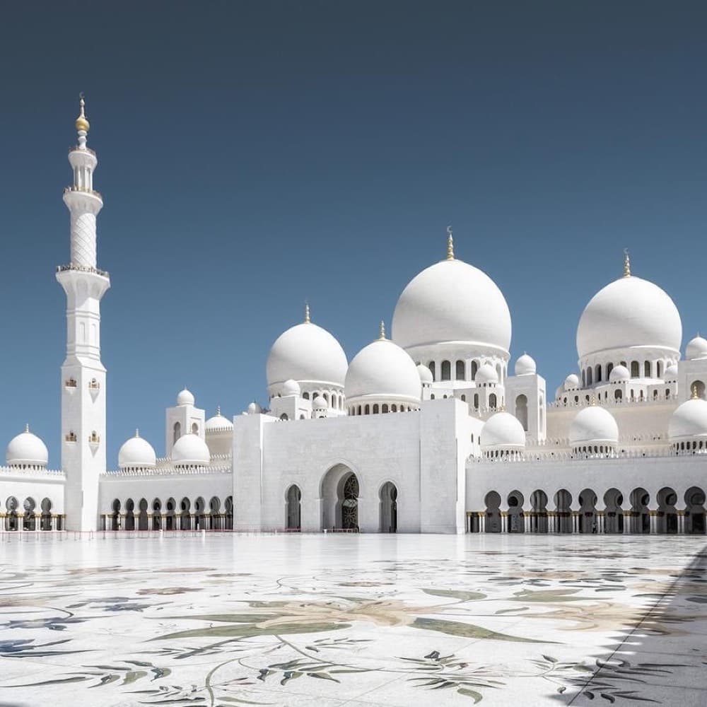 Sheikh Zayed Grand Mosque white domes and minarets glowing at twilight in Abu Dhabi