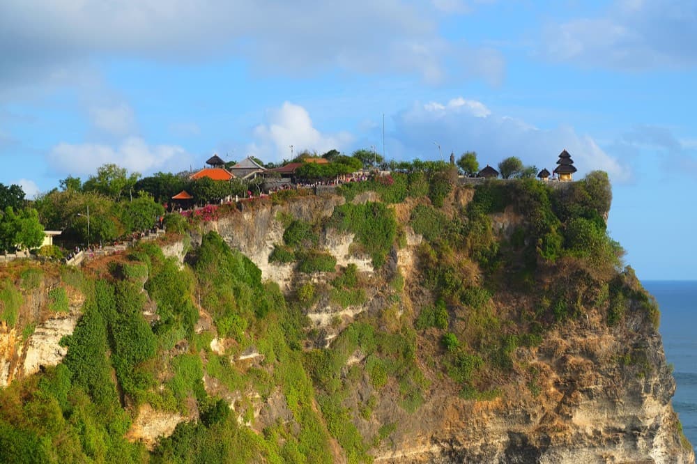 Terraced green rice paddies stepping down toward a Balinese temple and ocean