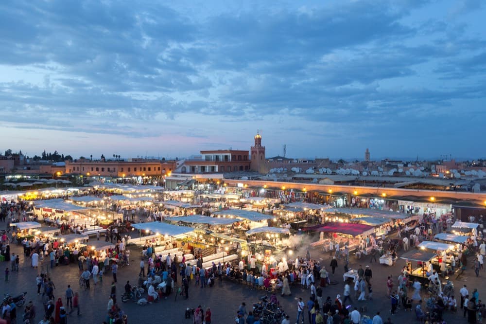 Koutoubia minaret rising over Marrakech rooftops with the snow-capped Atlas beyond
