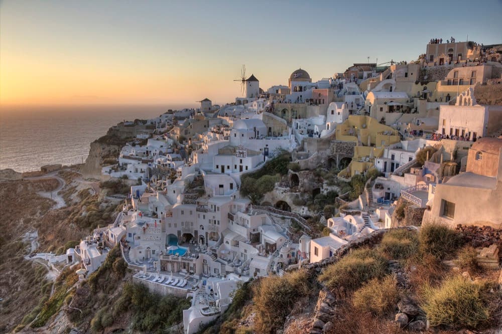 Whitewashed cliffside villages and blue domes above the Santorini caldera at sunset