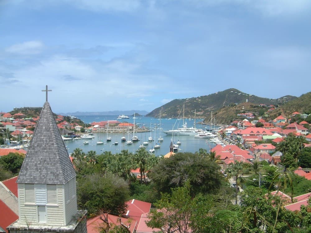 Gustavia harbor lined with superyachts below green hills on St. Barthelemy