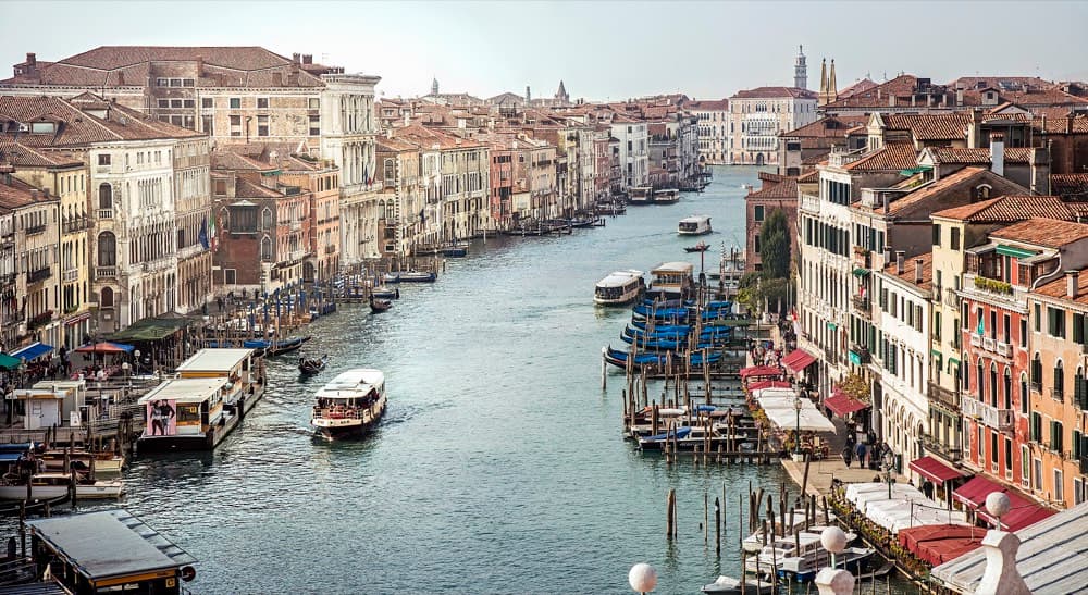 Grand Canal curving past domes and palazzi with gondolas at dawn in Venice
